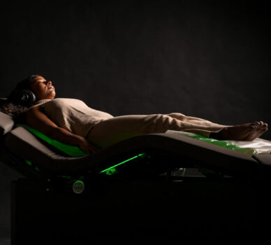 Woman relaxing on a luxurious massage chair in a serene, dimly-lit spa room at a hotel.
